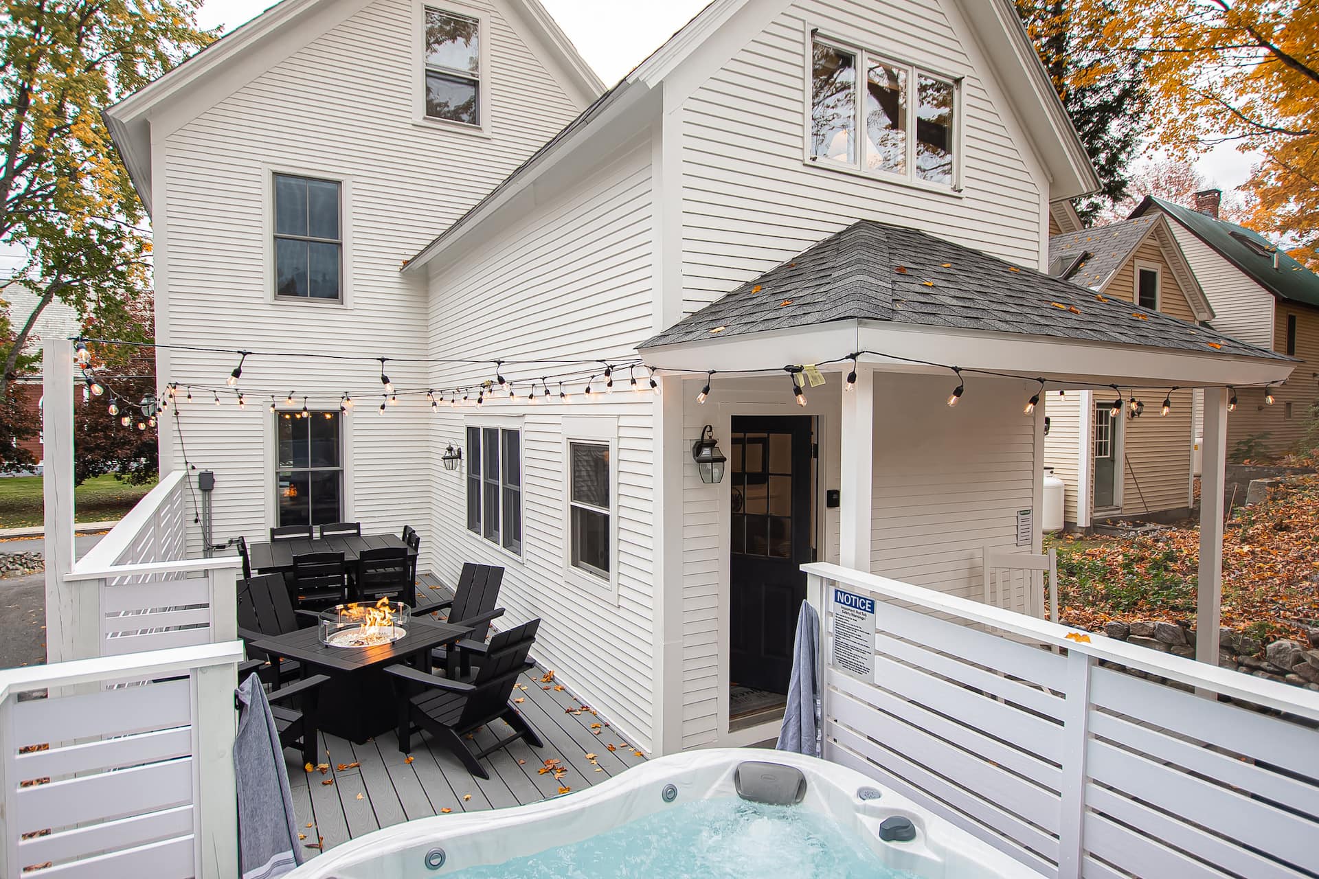 The deck at dusk — hot tub, fire pit and dining for eight under string lights