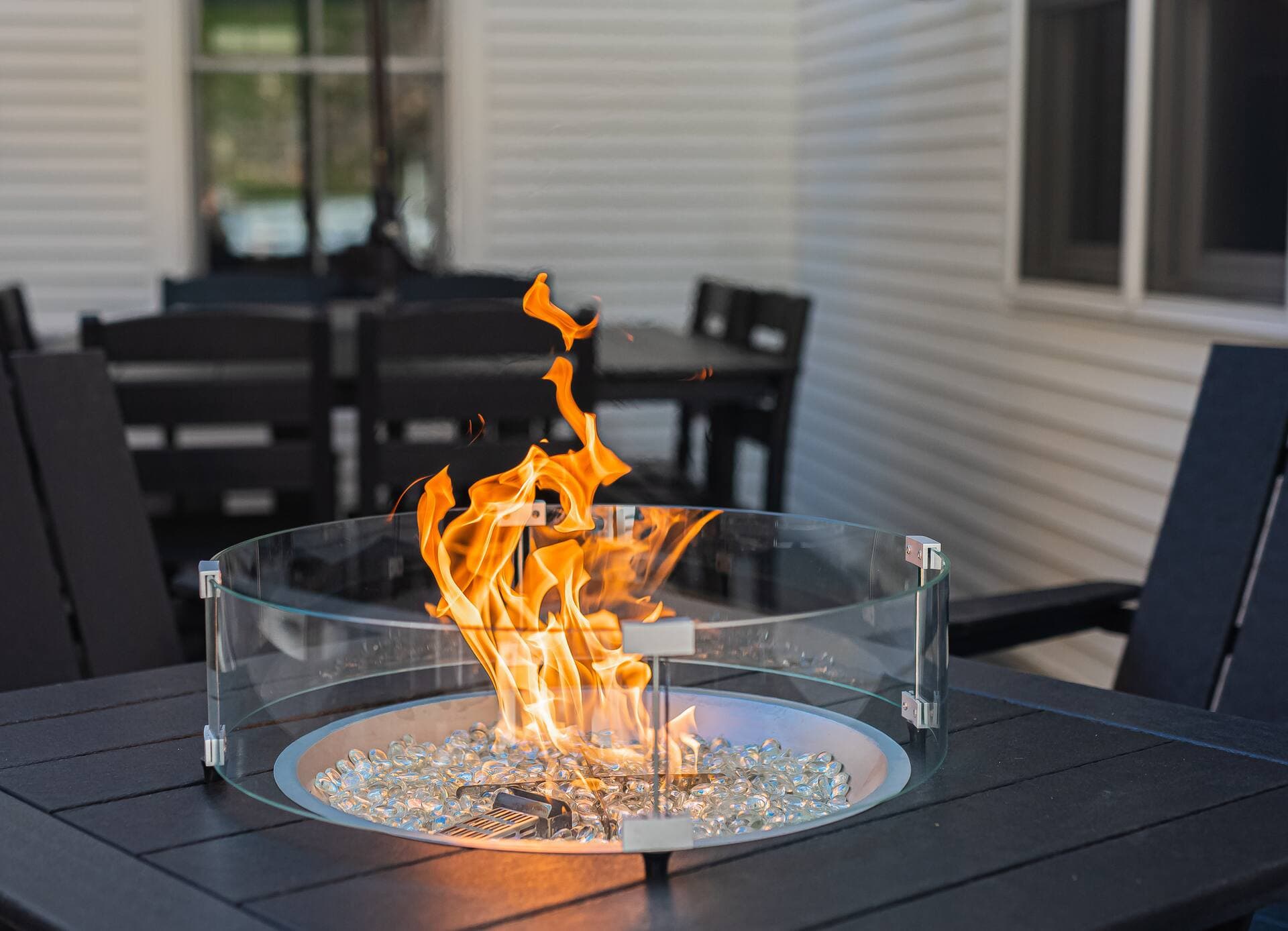 The propane fire pit lit at dusk, ringed with Adirondack chairs