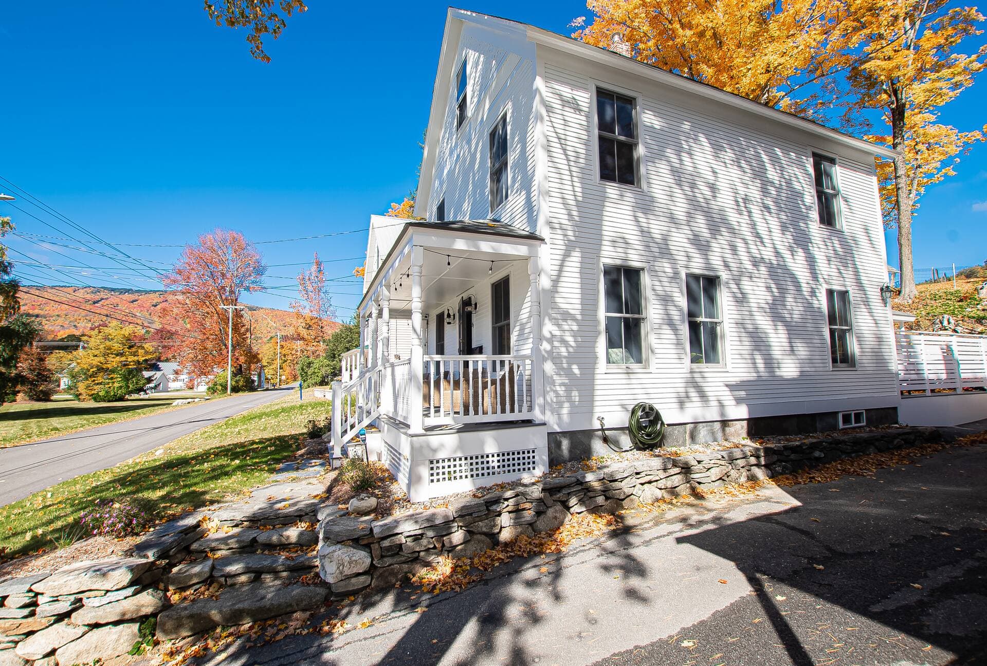 The white 1900 colonial from the street, autumn foliage